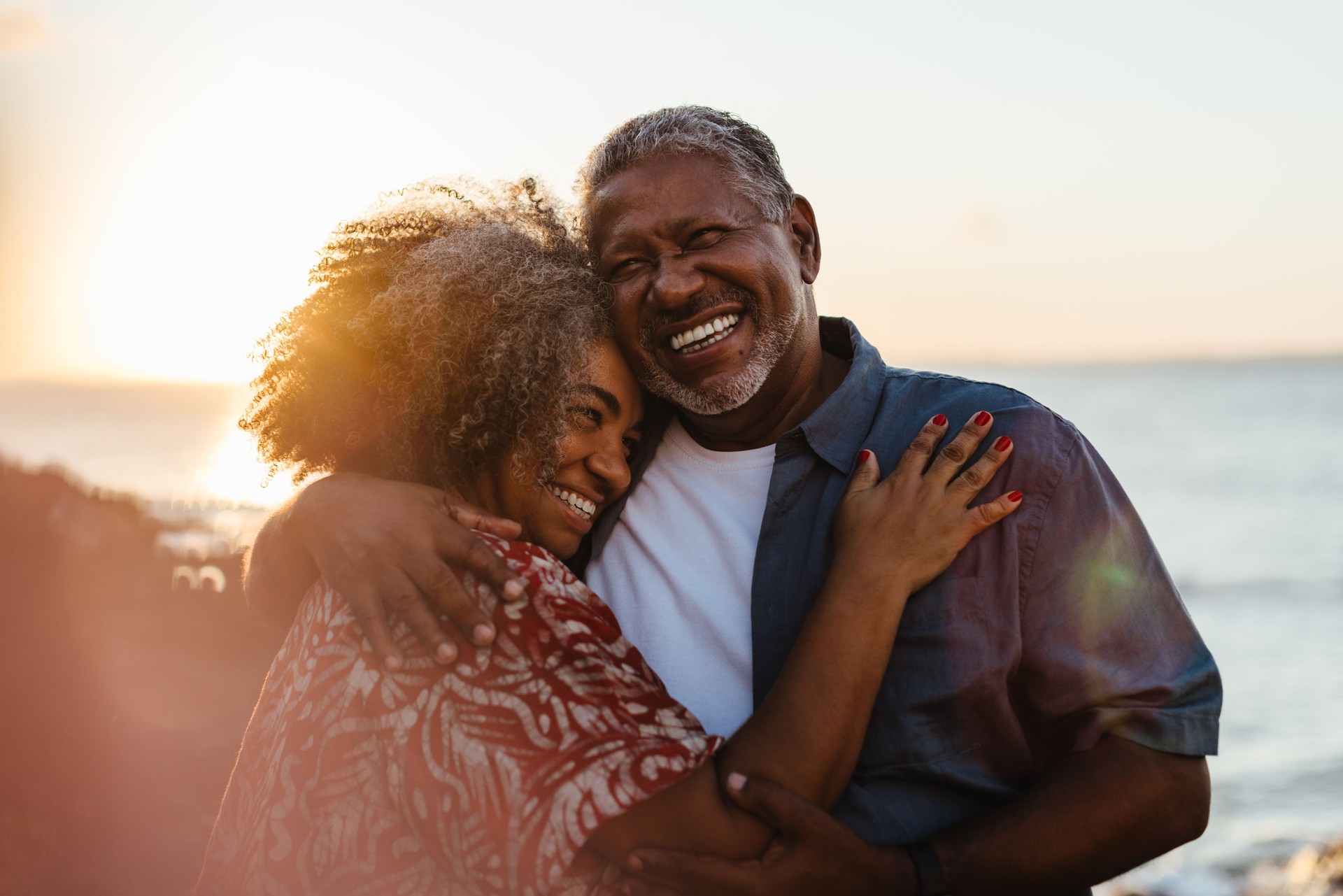 Elderly pair embracing at sunset, sharing joy and love by the seaside
